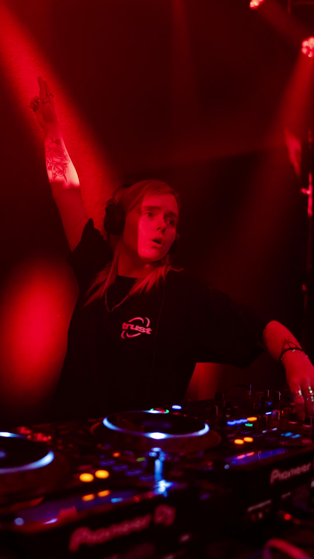 DJ with arm raised under red light