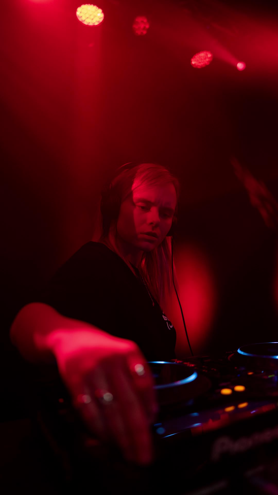 DJ reaching for the decks in red light